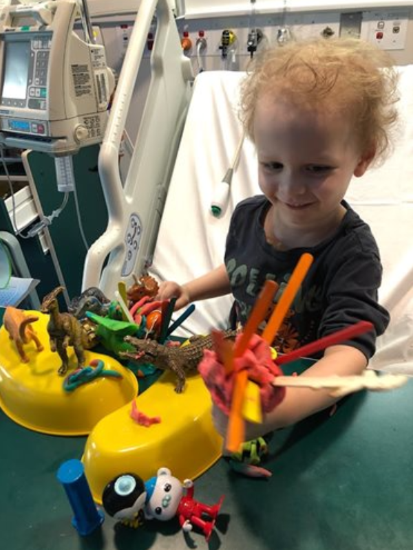 Bradley in hospital playing with playdough and dinosaurs